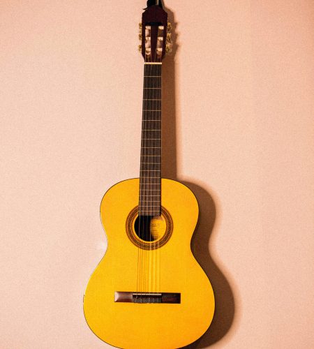 Yellow acoustic guitar hanging on a wall, showcasing its design and craftsmanship.